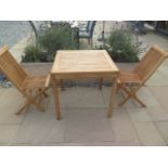 A new boxed teak bistro table 70cm x 70cm and two folding dining chairs.