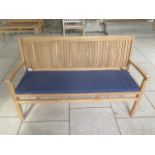 A teak hardwood bench with a blue cushion 150cm wide