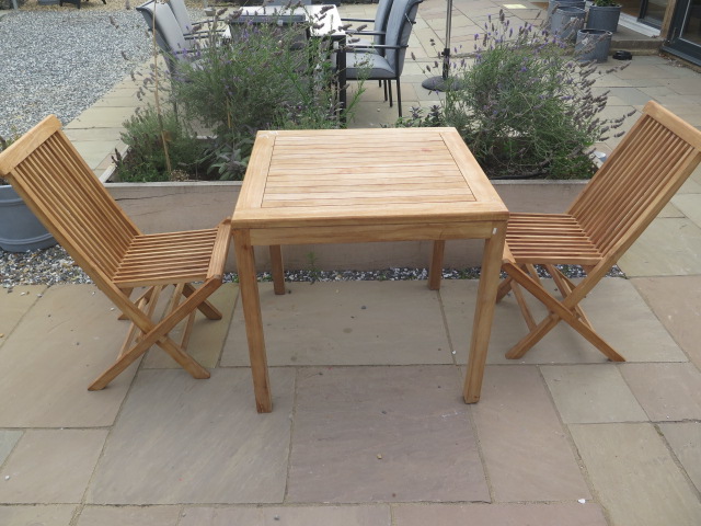 A new boxed teak bistro table 70cm x 70cm and two folding dining chairs.