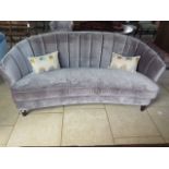 A grey upholstered banana shaped sofa, 90 cm tall x 213 cm wide x 100 cm