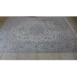 A hand knotted woolen rug with a light blue field 3.5m x 2.47m. Some light wear but generally good.