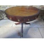 A mahogany drum table with a leather inset top on a standard column and tripod base terminating on