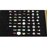 A collection of 54 silver dress rings in a jewellery display case