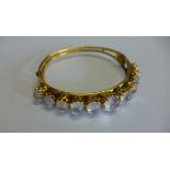 A 9ct yellow gold moonstone bangle. 6.5cm x 6.5 cm, approx 14.5 grams. Missing safety chain, some
