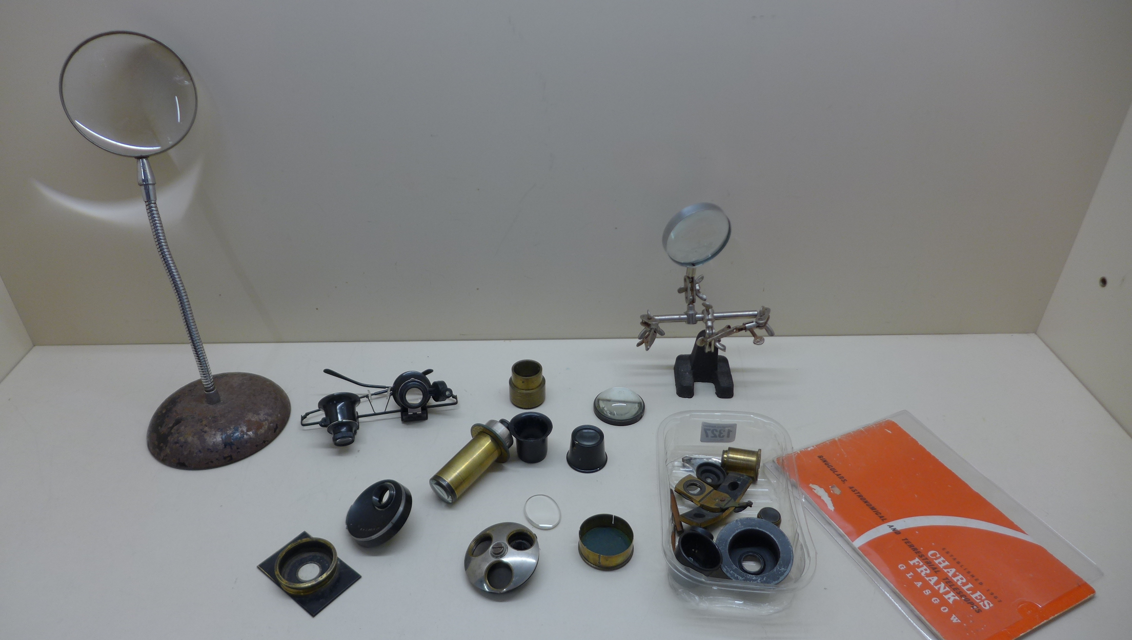A collection of microscope accessories, mainly brass, together with various magnifying lenses and an