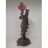 A bronze effect lady figure with a cranberry oil lamp on a bronze base, signed to base of figure,
