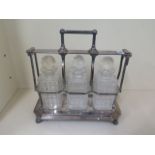 A silver plated 3 bottle tantalus, 38cm tall, 37 x 17cm. Some wear to plated and small chips to