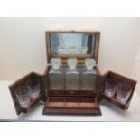 A Victorian oak 3 bottle games tantalus by Mansfield of Dublin, replacement decanters and glasses
