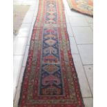 A hand knotted woollen runner with general overall wear and some holes, 445cm x 100cm. Removed