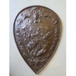 An ornate cast iron shield shaped plaque with classical decoration of a battle scene, 65cm x 46cm,