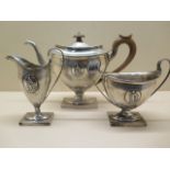 A three piece silver tea set with relief cast figural oval, hallmarked Sheffield 1909-1910, makers