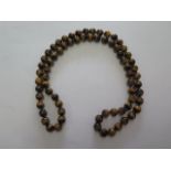 A string of tigers eye beads, each bead approx 1cm diameter, approx 80cm long, generally good