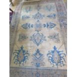 A cream ground rug with wide foliate border, 3m x 2.03m, two thirds wide heavy sun fading and