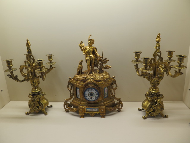 A Louis XVI style gilt metal mantel clock with a figural surmount and inset painted porcelain dial