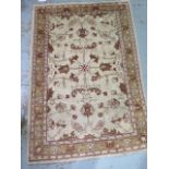 A hand woven woollen rug with cream ground and wide foliate border, 1.7m x 1.2m, minor wear and