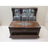 An oak three bottle tantalus with a base drawer and compartments, 31cm tall x 35cm wide x 27cm,