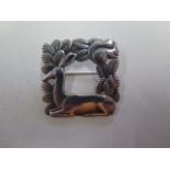 A silver brooch by Georg Jensen, square depicting a doe at rest and a squirrel with a leaf border,