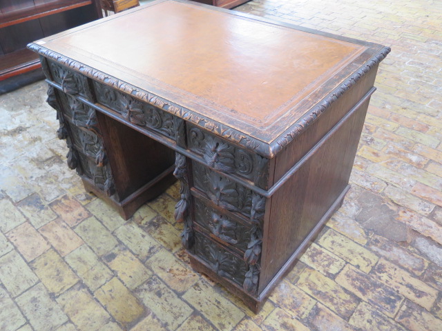 An oak kneehole writing desk with tooled leather top and ornate 'Green Man' carved drawers, 107cm - Image 2 of 6