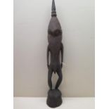 An African carved wooden anthropomorphic figure, the head and shoulders of elongated bird form, 52cm