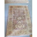 A hand woven woollen rug with mixed colour run with a wide foliate border, 1.8m x 1.28m, minor wear,