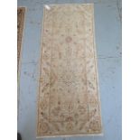 A hand woven woollen rug with cream ground with overall foliate decoration, 1.9m x .78m, minor