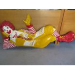 A vintage Ronald MacDonald fibreglass wall sign depicting Ronald in a recumbent pose leaning on