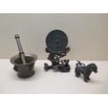 A Chinese bronze mirror, 10cm diameter, on an associated carved wooden stand, a bronze dog of Fo,