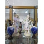 An early 20th century pair of continental bisque porcelain figures, each modelled next to a woven