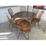 An oak tripod kitchen table with six ash and oak hoop back chairs, 74cm tall x 121cm diameter