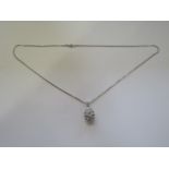 A hallmarked 18ct white gold open work egg shaped diamond pendant on an 18ct chain marked 750,
