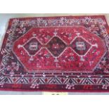 A hand knotted woollen rug with a red field, 2.25m x 1.61m, some small wear but generally good