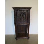 A 19th century Gothic oak tall cupboard with carved figural door over a single under tier, 137cm