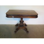 A 19th century rosewood folding tea table over foliate carved central support, four lion paw feet