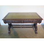 A Victorian oak sofa table writing desk with green leather and gilt tooled top over two carved