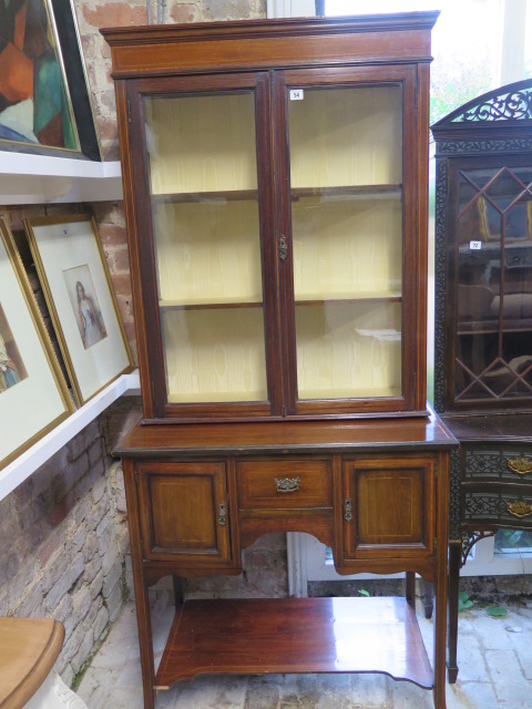 An Edwardian mahogany and line inlaid display cabinet, with glazed hinged doors enclosing two