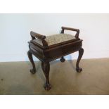 A Victorian mahogany piano stool with upholstered hinged seat and carved legs terminating on ball