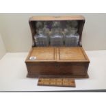 An oak three bottle tantalus games box with cribbage board, no makers name, all bottles are chipped