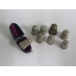Seven hallmarked silver thimbles and a white metal thimble in a case