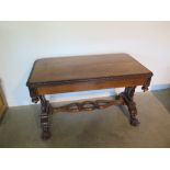 A Victorian oak sofa table with foliate carved detail to top and sides and lion paw feet united by a