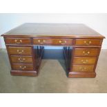 An 18 drawer mahogany partners desk with gilt topped green leather top over a double sided arrangem