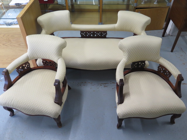 An Edwardian mahogany and upholstered salon suite comprising sofa and two armchairs, with cream