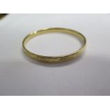 An 18ct yellow gold hinged bangle with a white gold slider, 6.2cm x 6.8cm, all round engraving,
