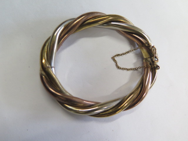 A 9ct tricolour gold hinged hollow bangle, 8cm x 6.8cm external, approx 36 grams, clasp working