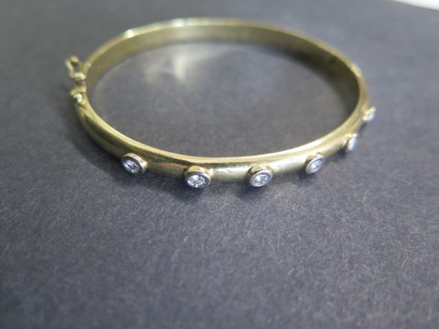 A yellow gold hinged bangle with 6 diamonds each approx 0.10ct, 6.5cm x 5.5cm external diameter,