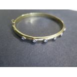A yellow gold hinged bangle with 6 diamonds each approx 0.10ct, 6.5cm x 5.5cm external diameter,