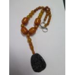 A jade and jade type amber pendant, necklace 40cm long, pendant 5cm x4cm, largest bead approx 2cm