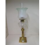 A brass oil lamp with clear glass reservoir and green tinted shade, 67cm tall, in good condition and