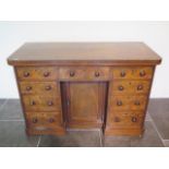 A Victorian mahogany nine drawer desk / dressing chest with a central cupboard, 82cm tall x 127cm