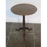 A Georgian mahogany tripod wine table circular top with raised lip over a slim turned column and