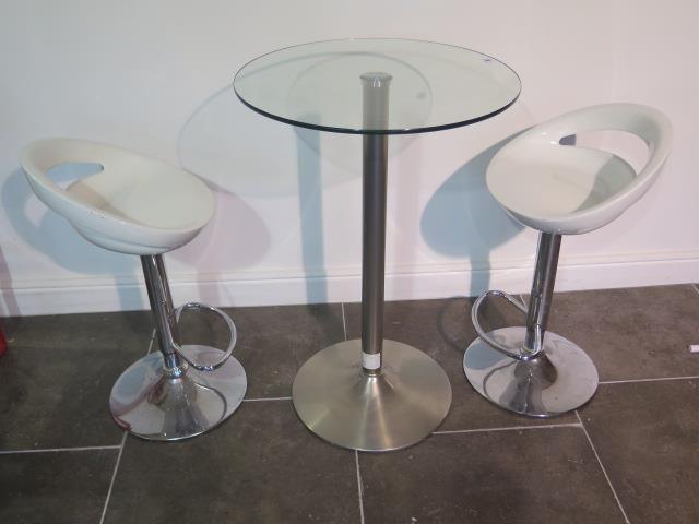 A glass top bar table, 91cm tall, with two moulded white seats gas lift stools, some usage marks but